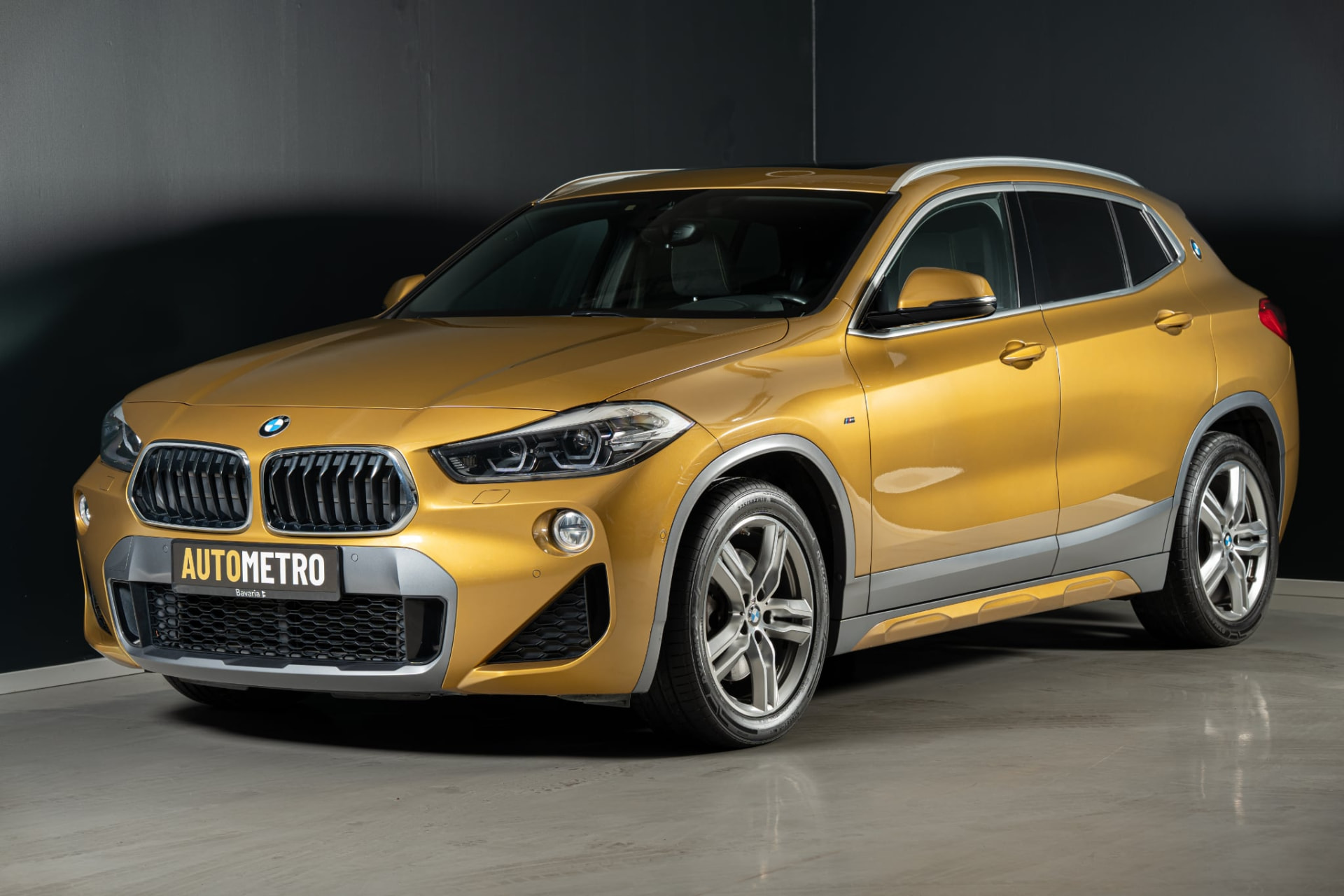 Premium gold BMW SUV in the atmospheric Autometro showroom